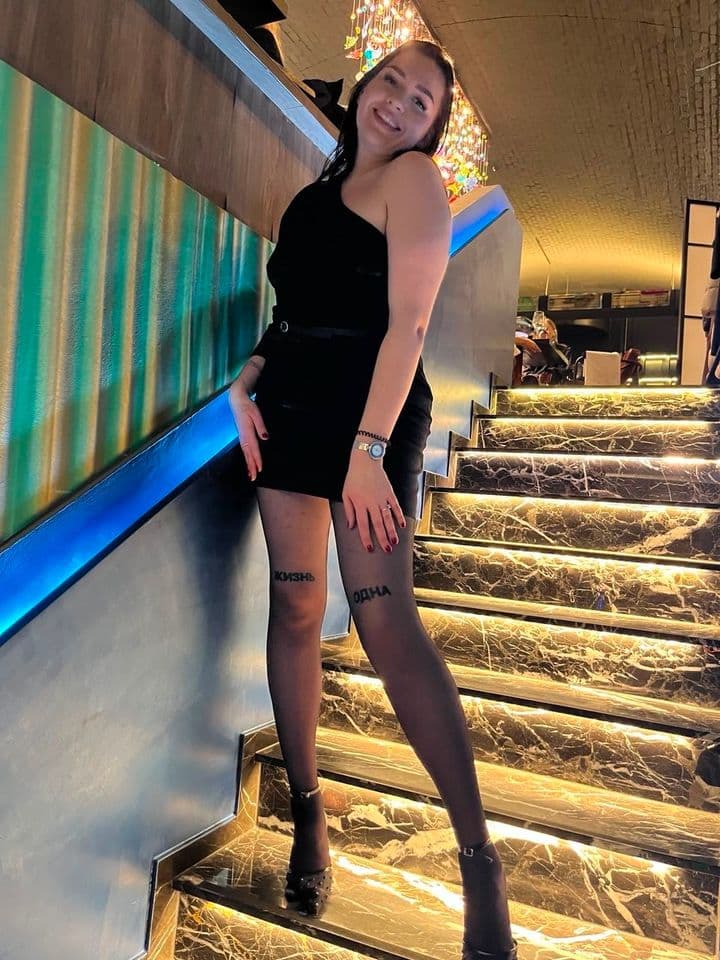 Lana im schwarzen Minikleid auf der Treppe – Authentische Erotikmassage Berlin.
